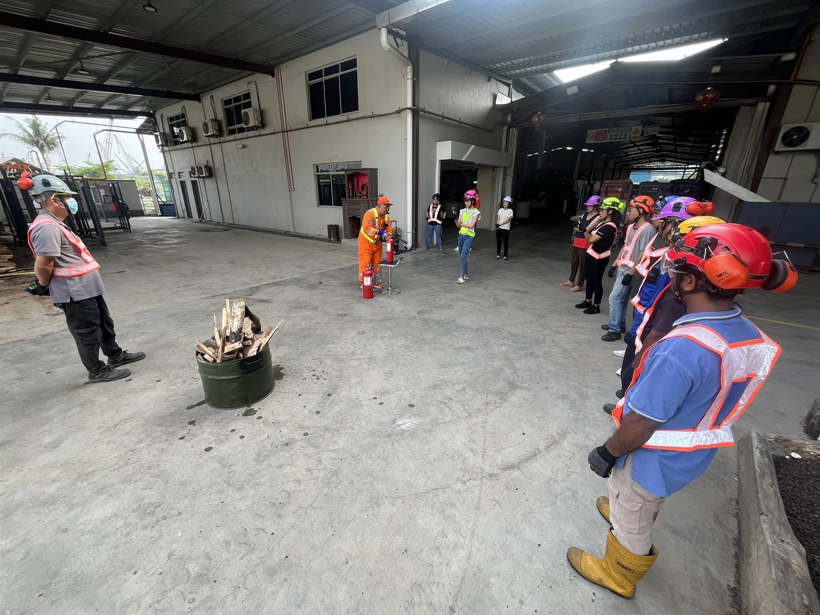 Workers participating in a fire safety drill with extinguisher demonstration