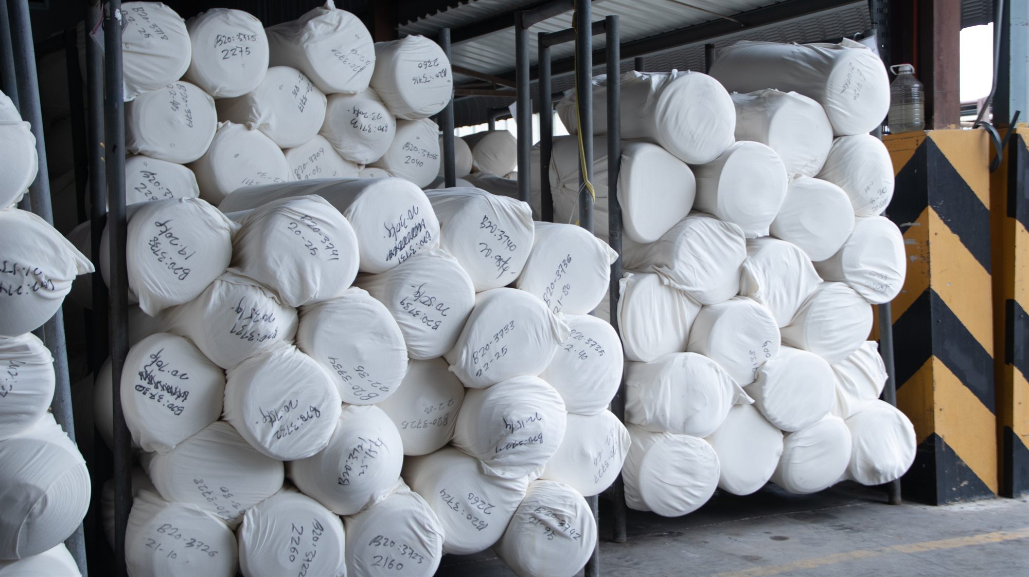 Greige fabric rolls received from partner knitting factories — labeled and racked